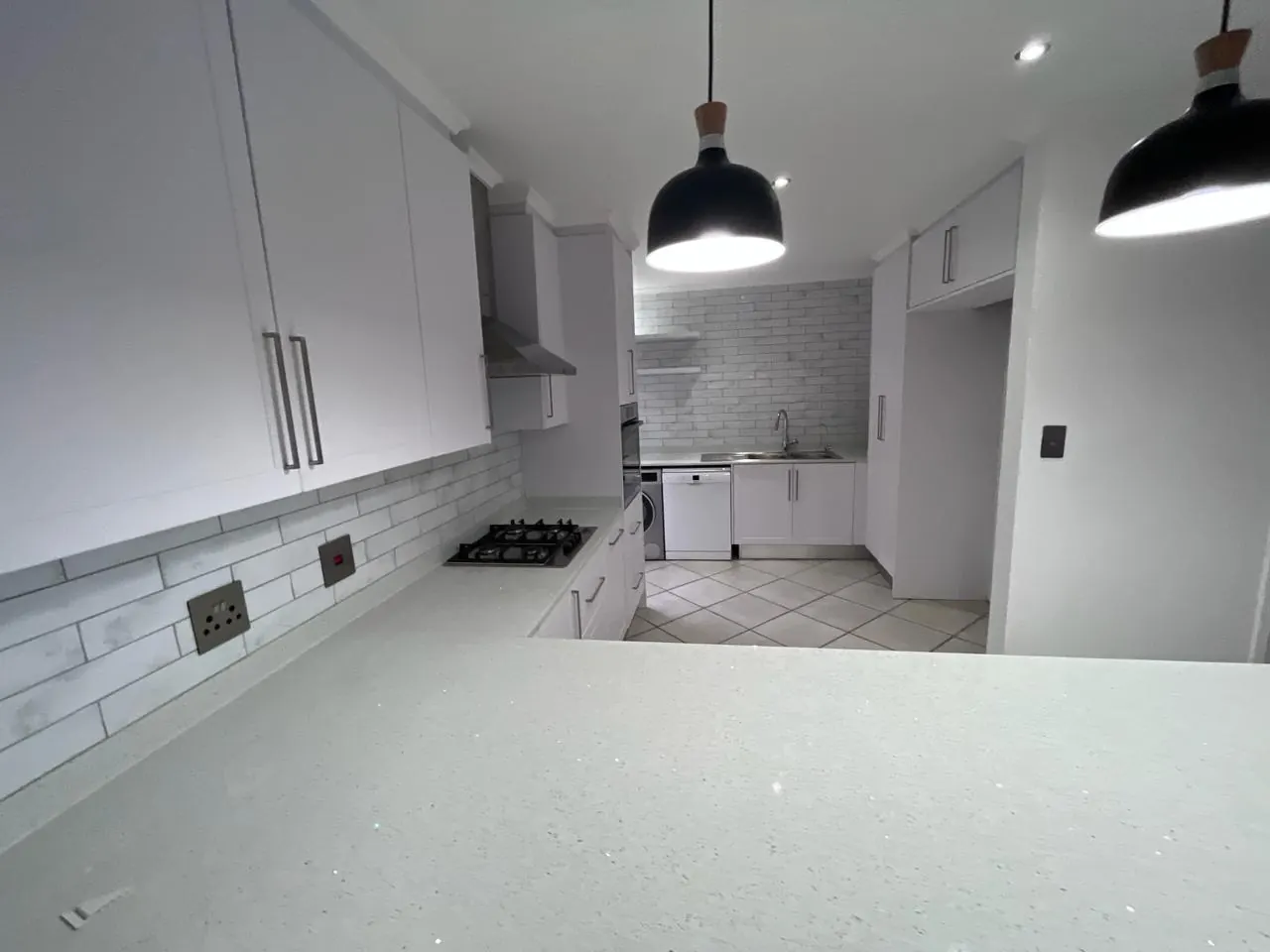 After: gas hob, extractor and white wall units with brick-look splashback tiles