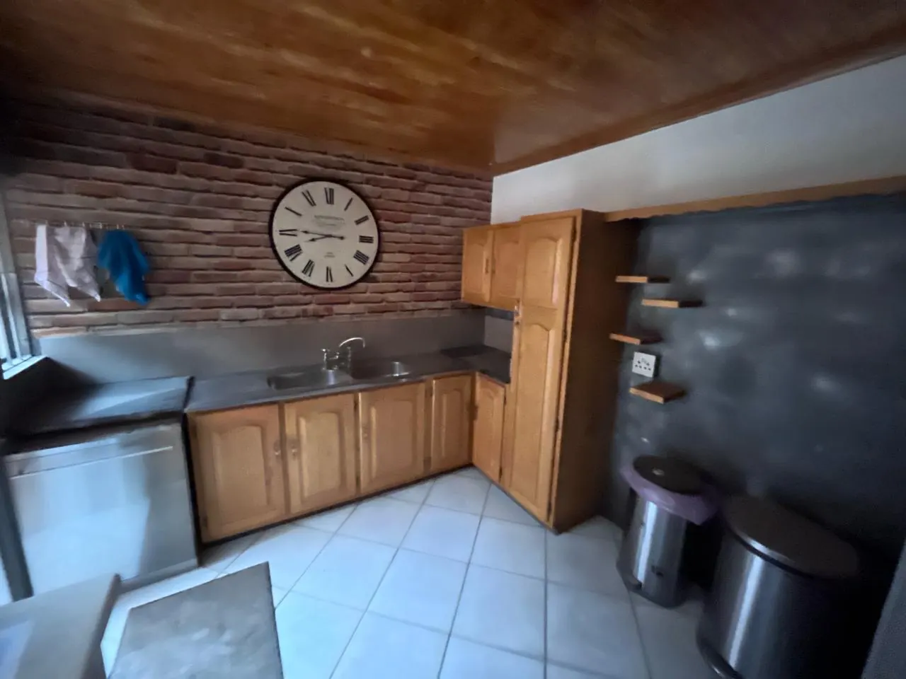 Before: dated kitchen with honey-oak cupboards, steel worktops and a timber ceiling