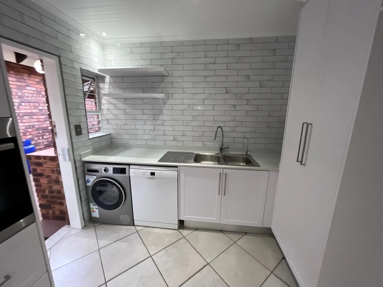 After: scullery with double sink, floating shelves and bays for washing machine and dishwasher