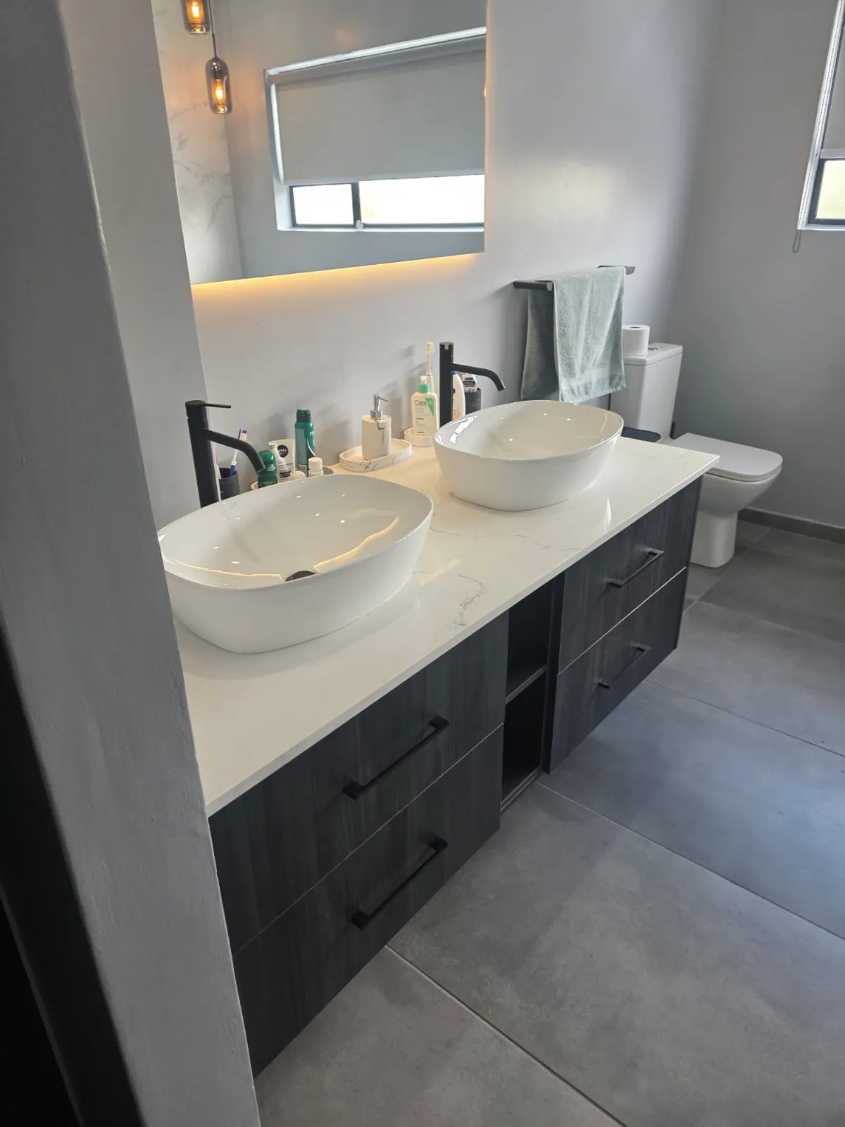 Dark timber-look floating vanity with drawers, open shelf and white stone-look top
