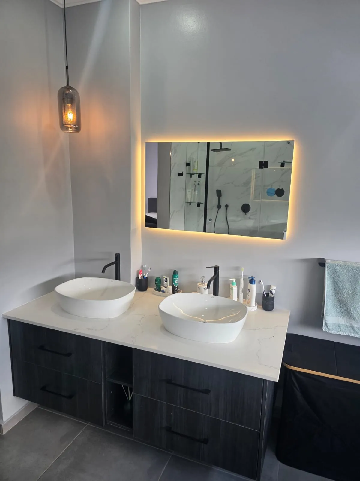 Floating double vanity with two vessel basins, stone-look top, black tall mixers and backlit LED mirror