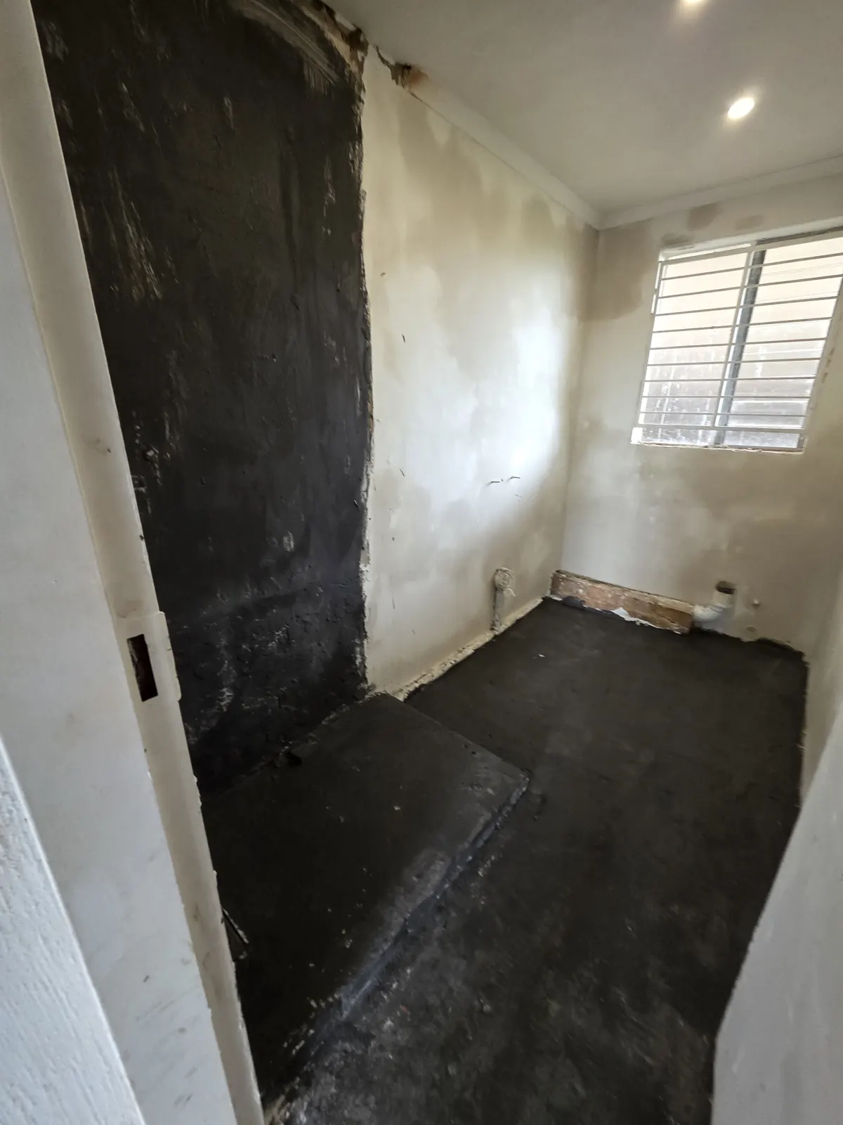 During: bathroom stripped to the walls, with waterproofing applied to the shower area and floor before tiling