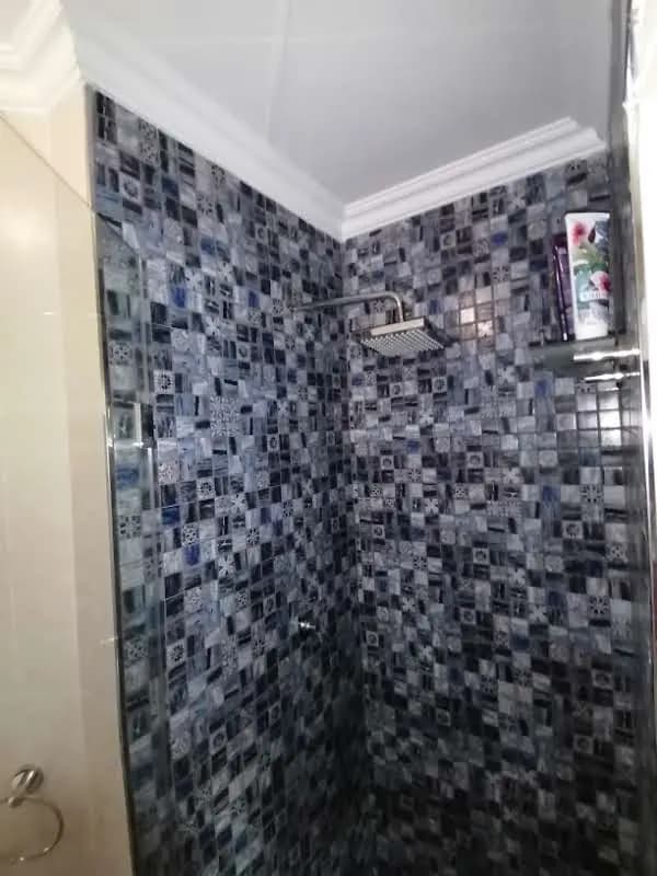 Shower tiled floor to ceiling in blue-grey glass mosaic with a square rain shower head