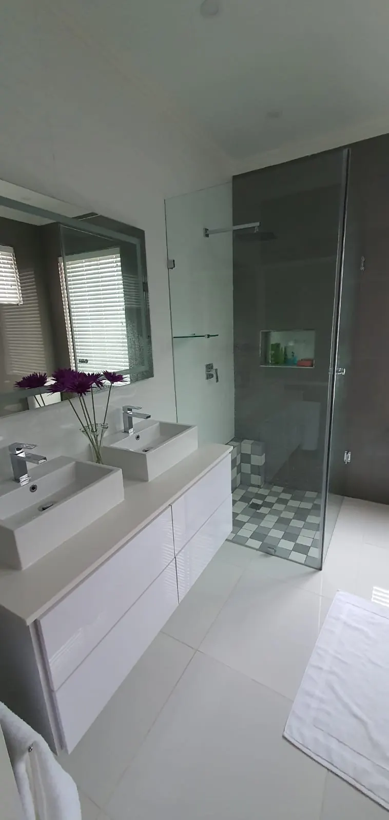 Bathroom with long vanity, mirror and walk-in shower with patterned floor tiles