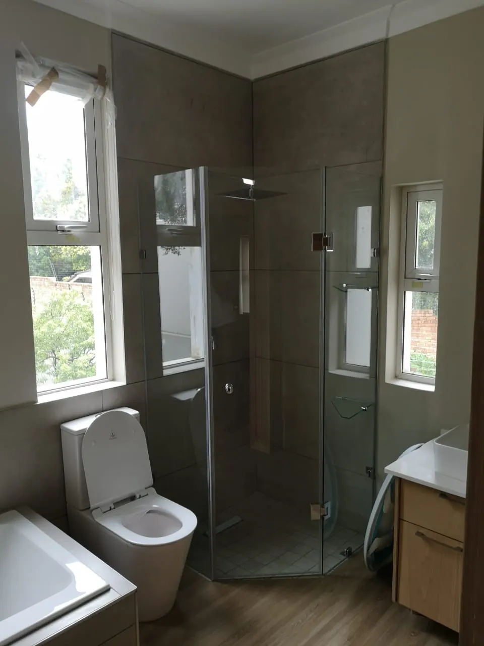 Bathroom with frameless glass corner shower and dark grey wall tiles