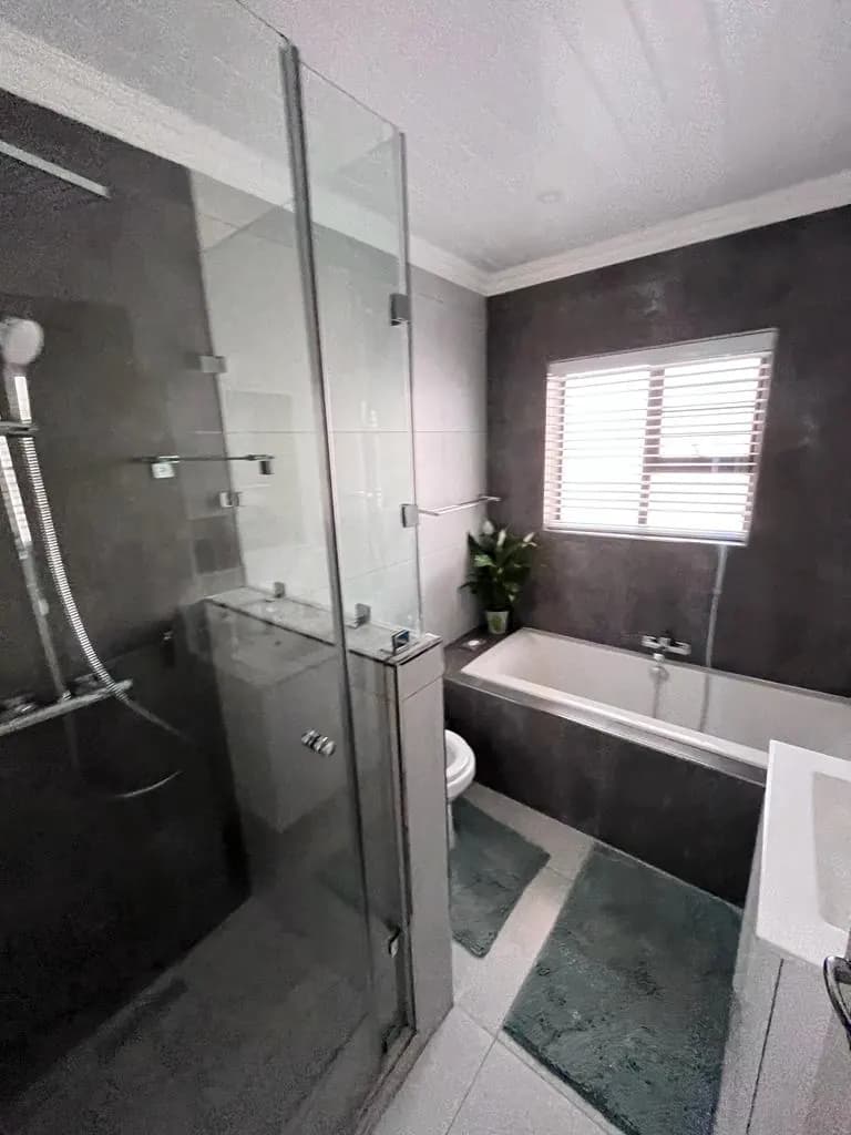 Bathroom with frameless glass shower, built-in bath and charcoal wall tiles