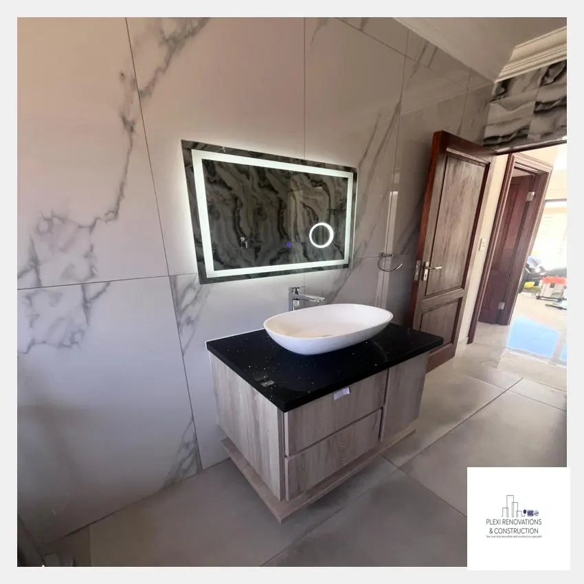 LED backlit mirror above a vessel basin on a dark-topped vanity