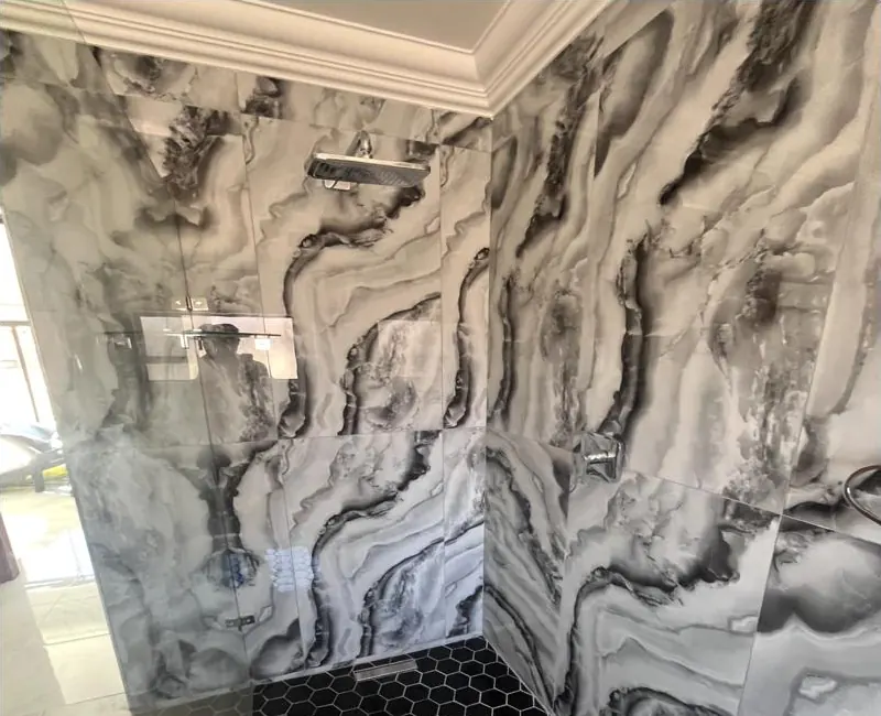 Walk-in shower with large grey marble-effect wall tiles and black hexagon mosaic floor