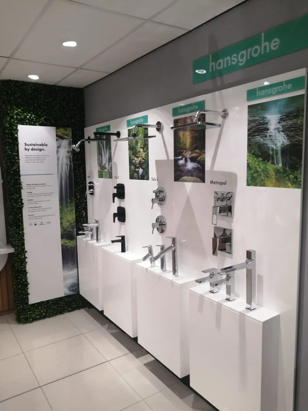 Bathroom fittings showroom display wall with white plinths and a green feature wall
