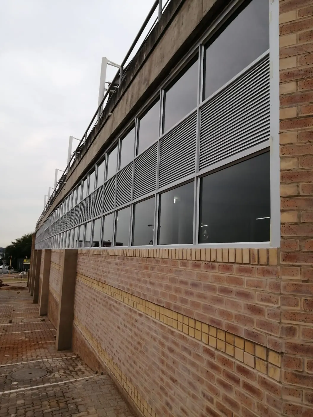 Commercial building facade with a long run of new aluminium windows and louvre panels above face-brick walls