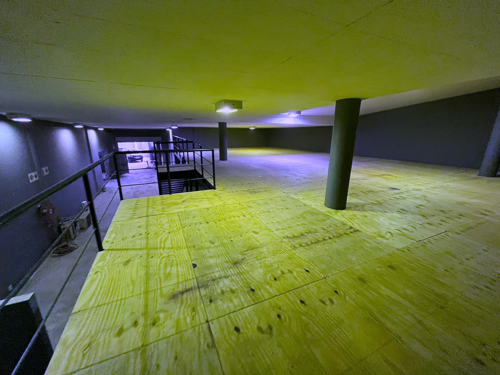 Mezzanine floor seen from the stair head, with steel balustrade and plywood decking