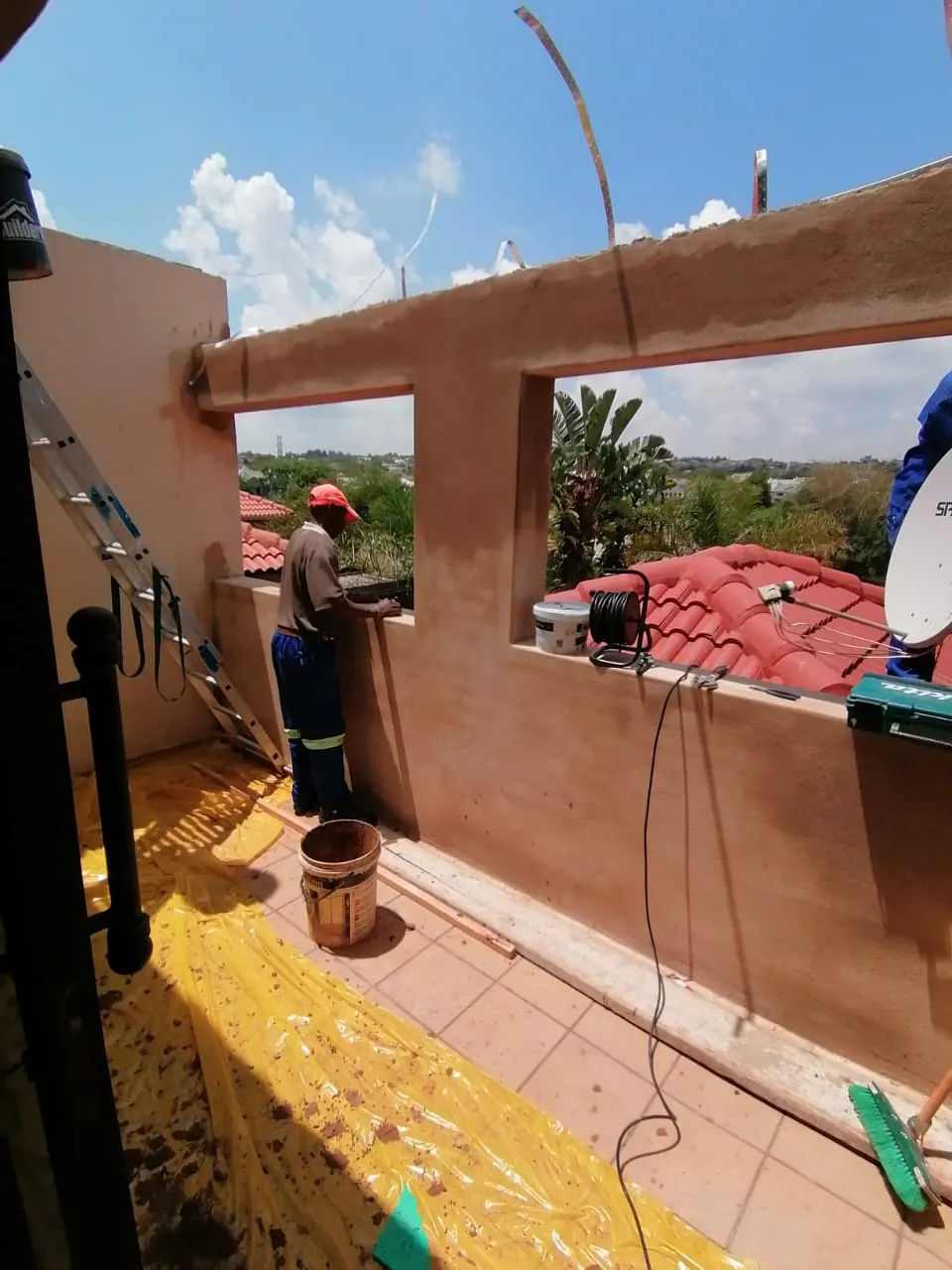 Team building a new parapet wall with openings on an upstairs balcony