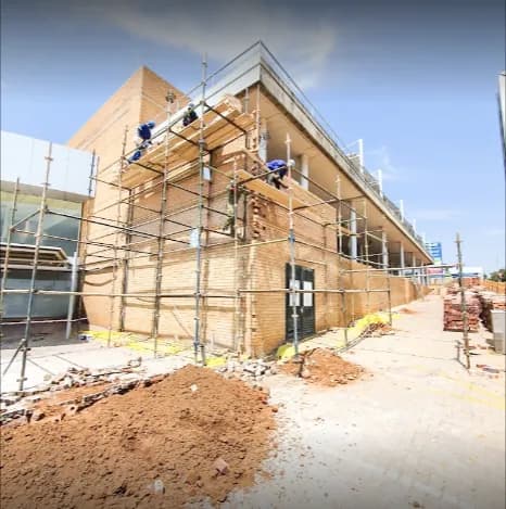 Brickwork going up on a two-storey commercial building, with scaffolding and the team working on the upper level