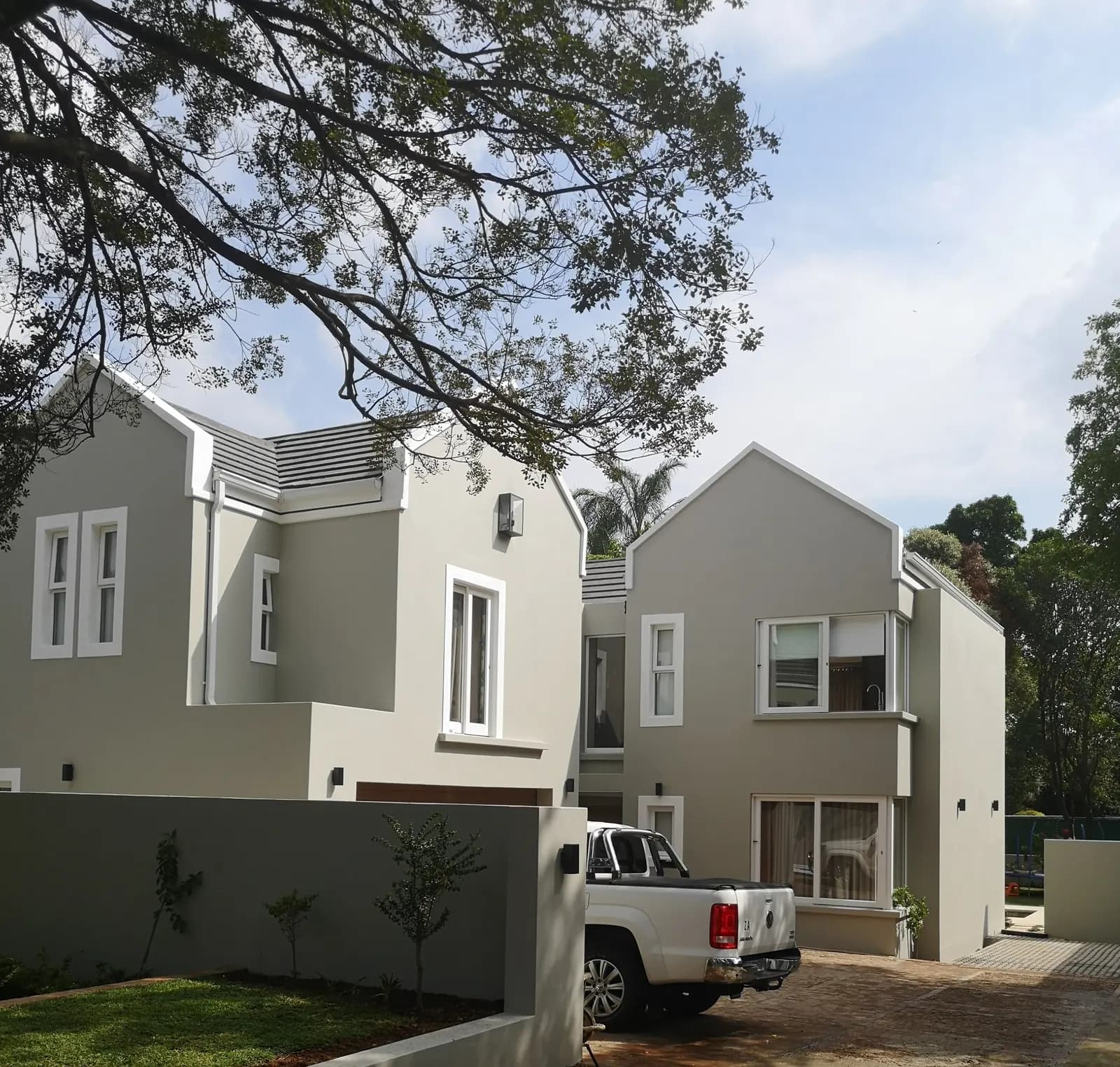 Two newly built double-storey houses with grey plaster and pitched roofs