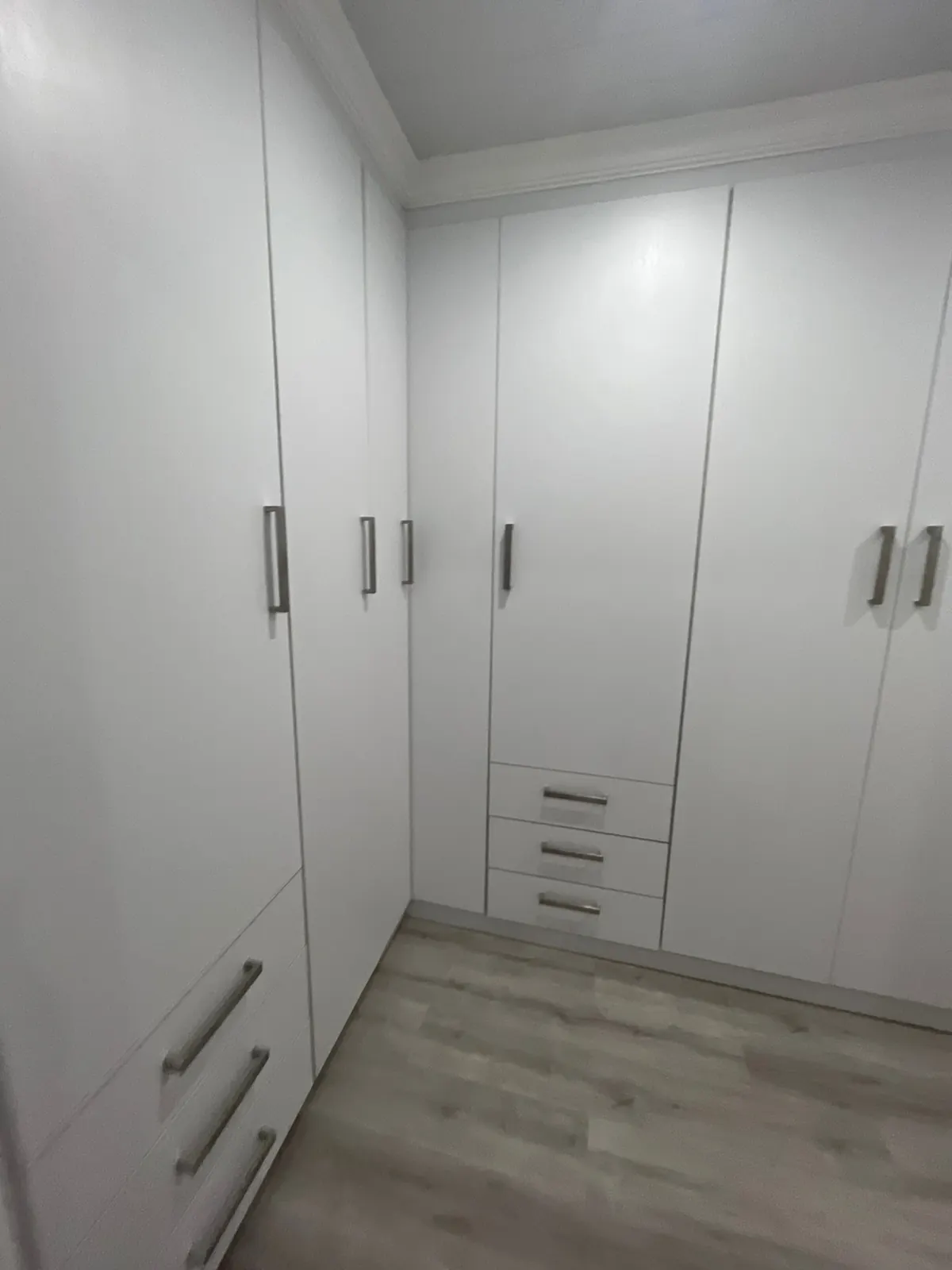 Corner walk-in wardrobe with white doors and drawer units