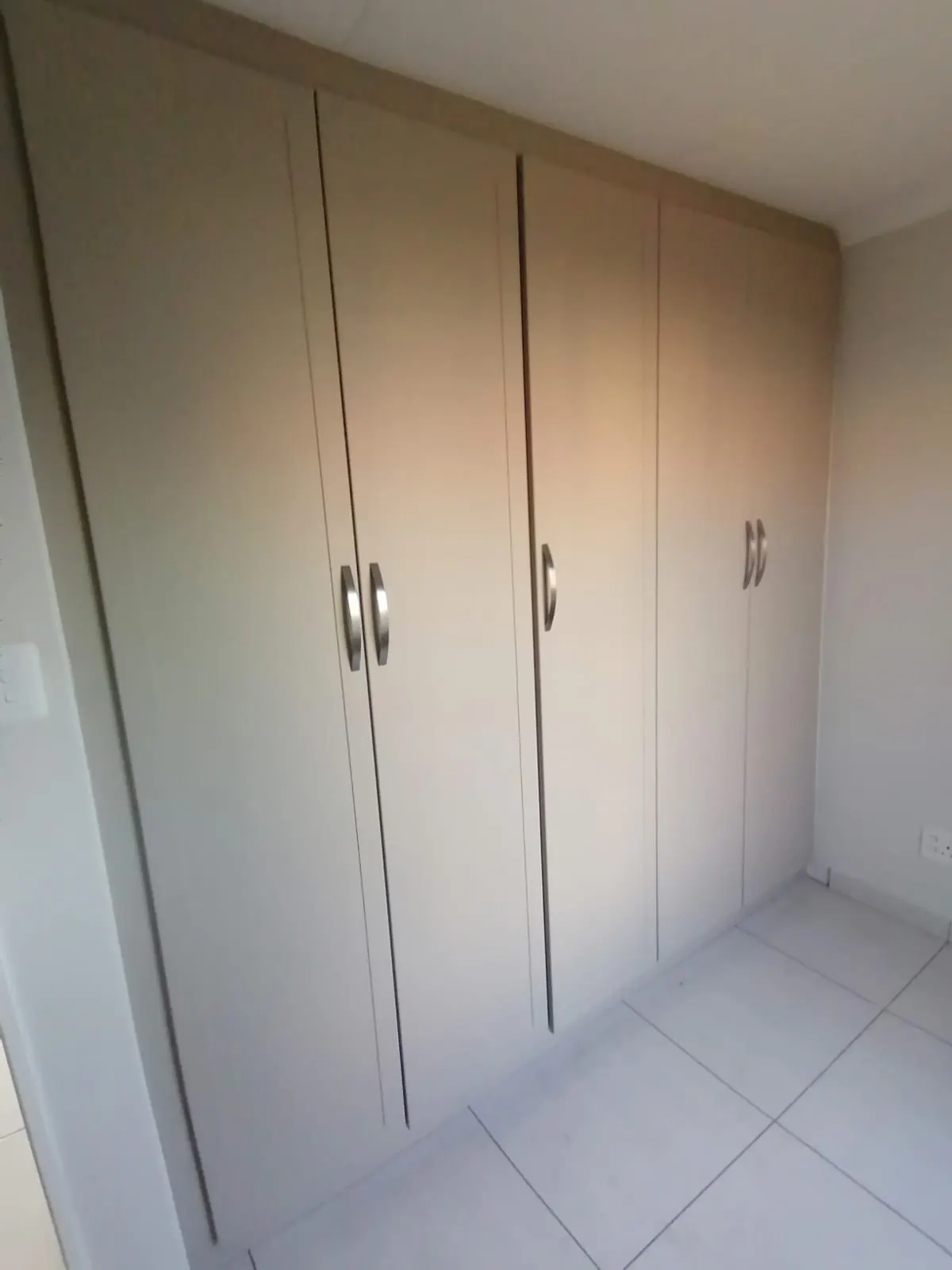 Cream built-in bedroom cupboards with curved handles