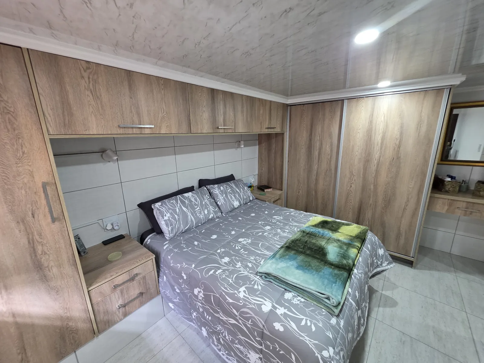 Bedroom with oak-look built-in cupboards, overbed units and sliding wardrobe doors