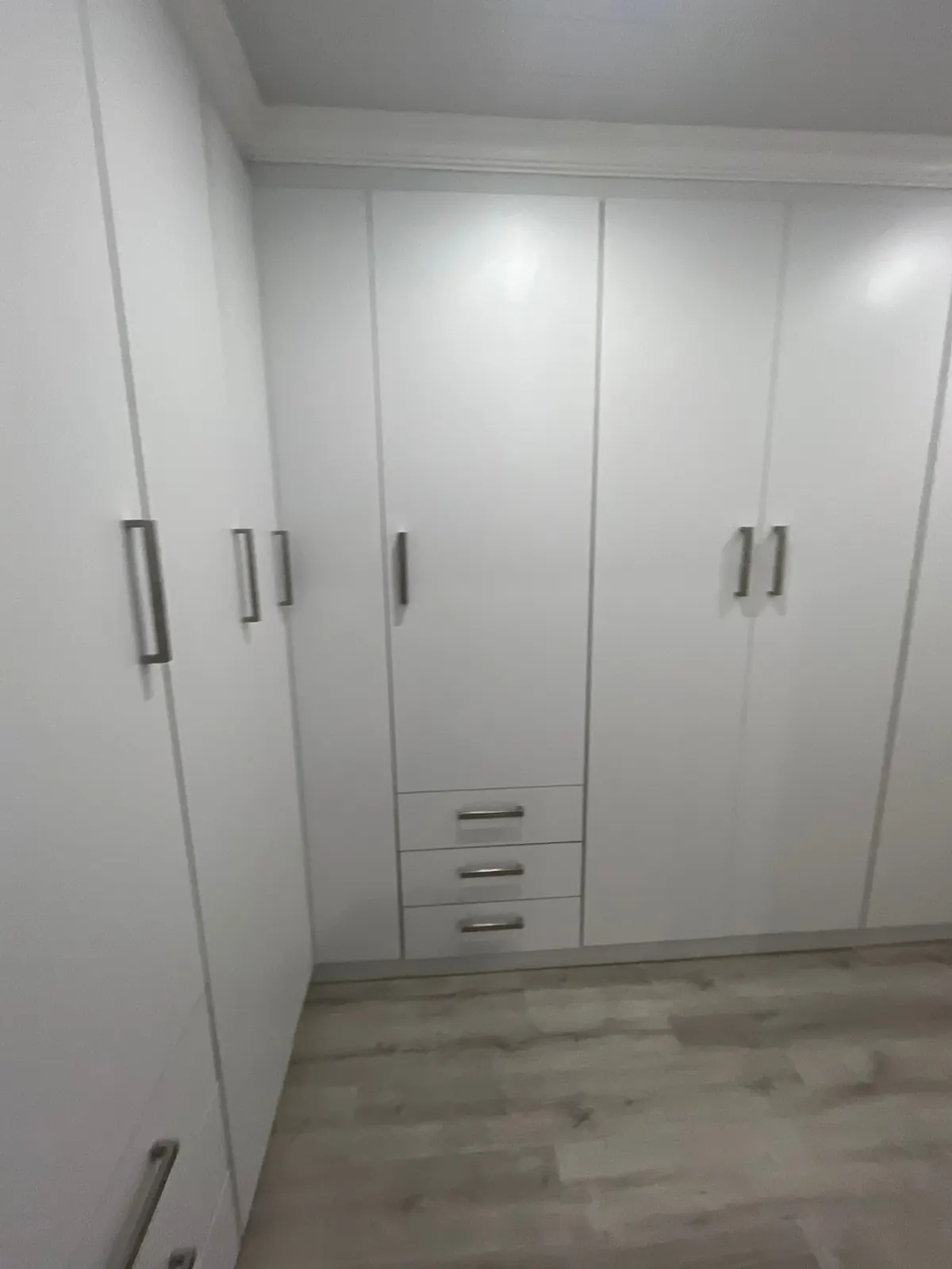 L-shaped white built-in cupboards with drawers