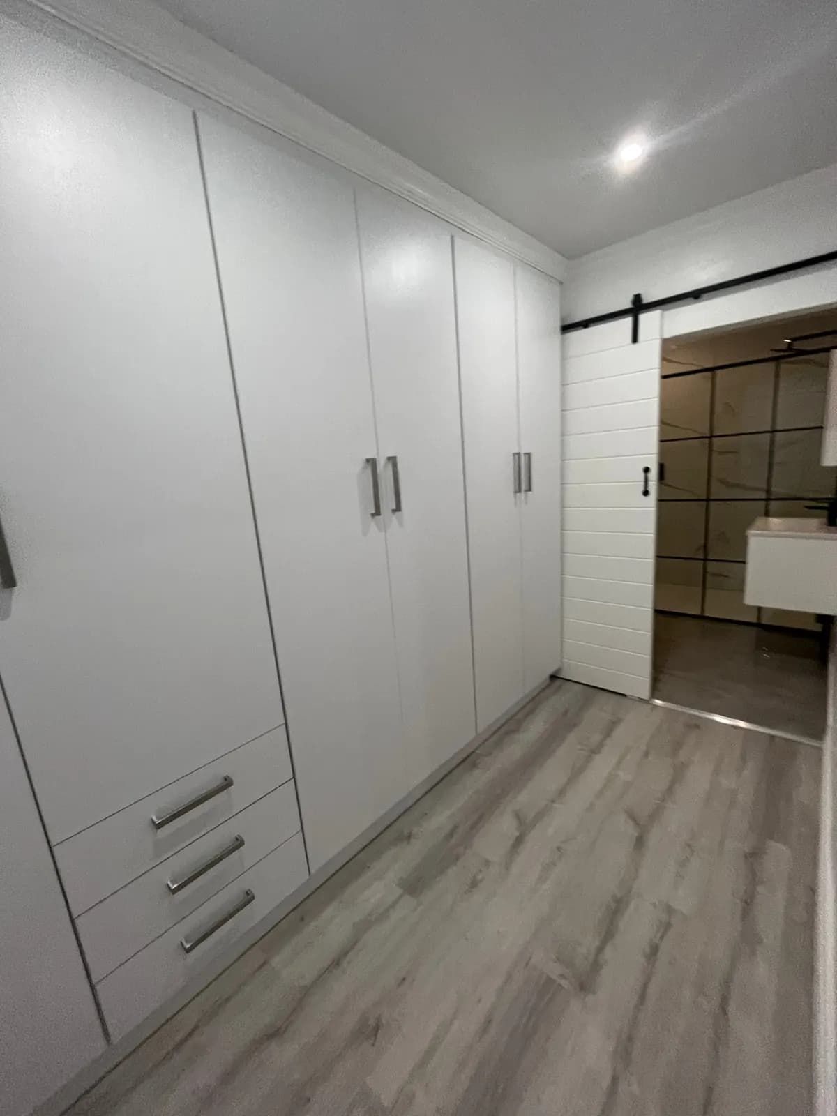 Full wall of white wardrobe doors with drawers and cornice