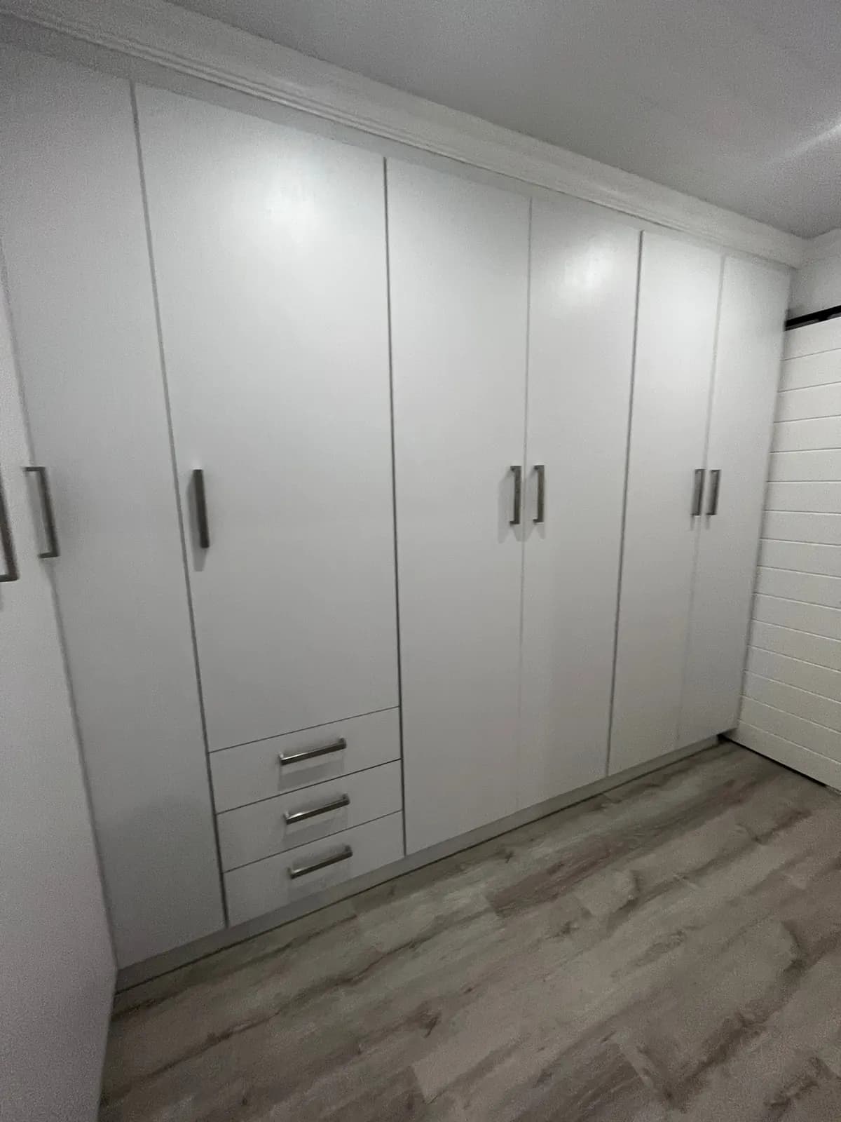White floor-to-ceiling wardrobes with laminate flooring