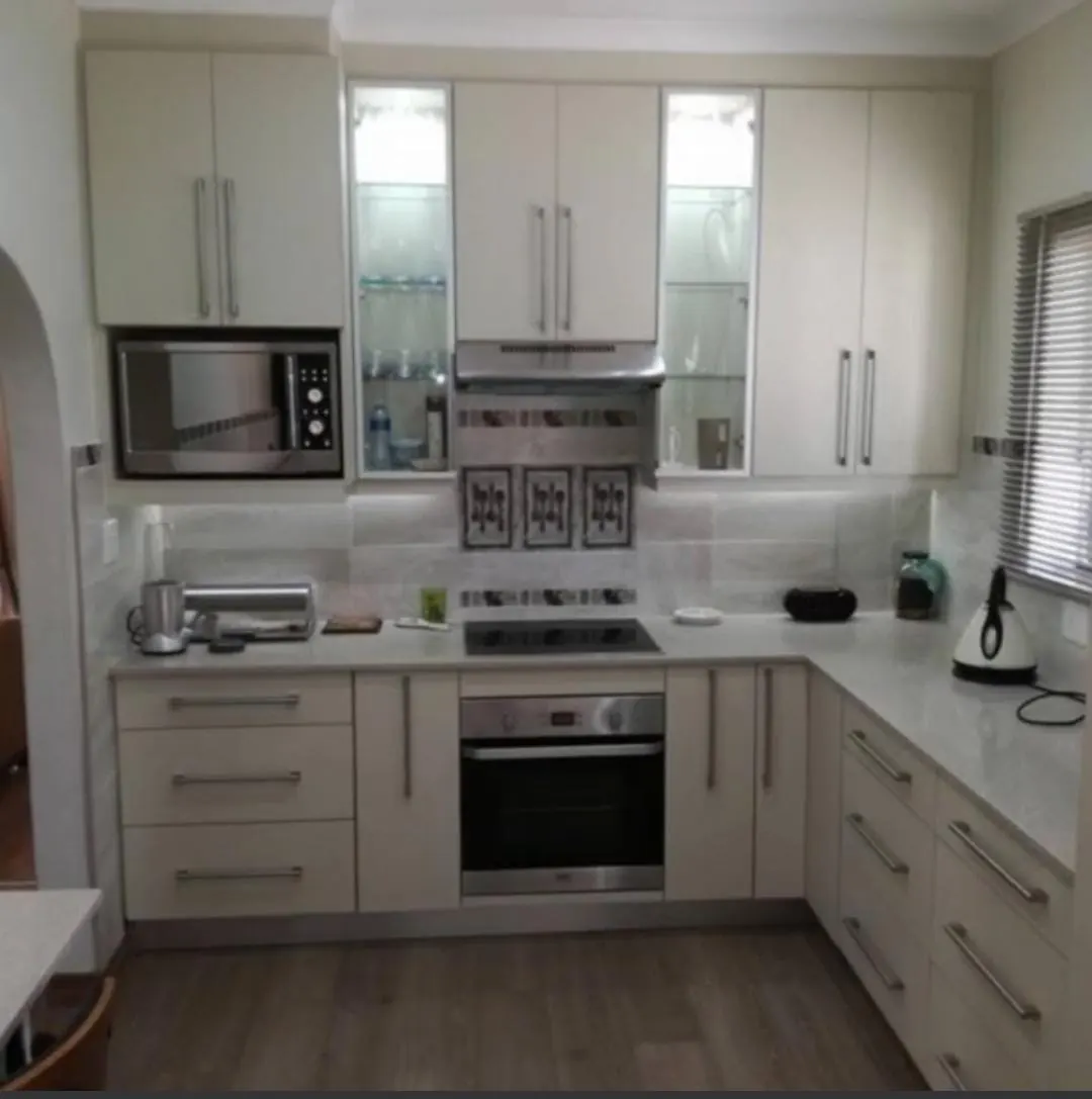 Cream U-shaped kitchen with lit glass cabinets and a built-in oven