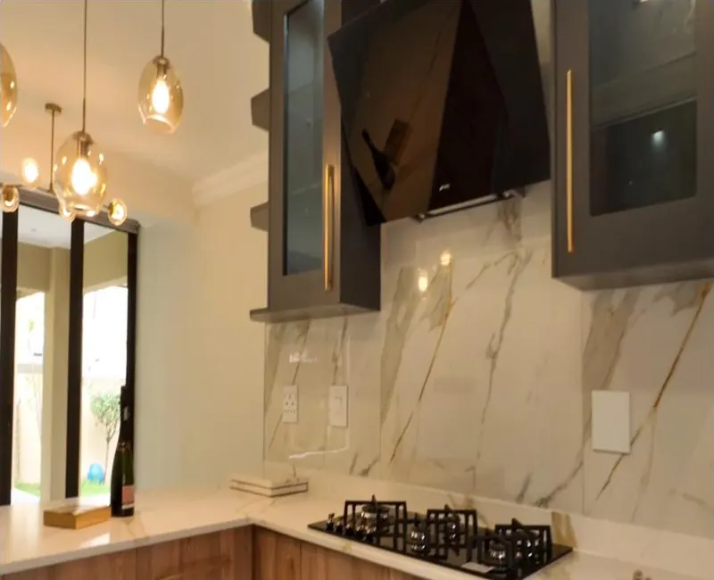 Gas hob with marble-look full-height splashback, dark glass wall units with gold handles and timber-look drawers