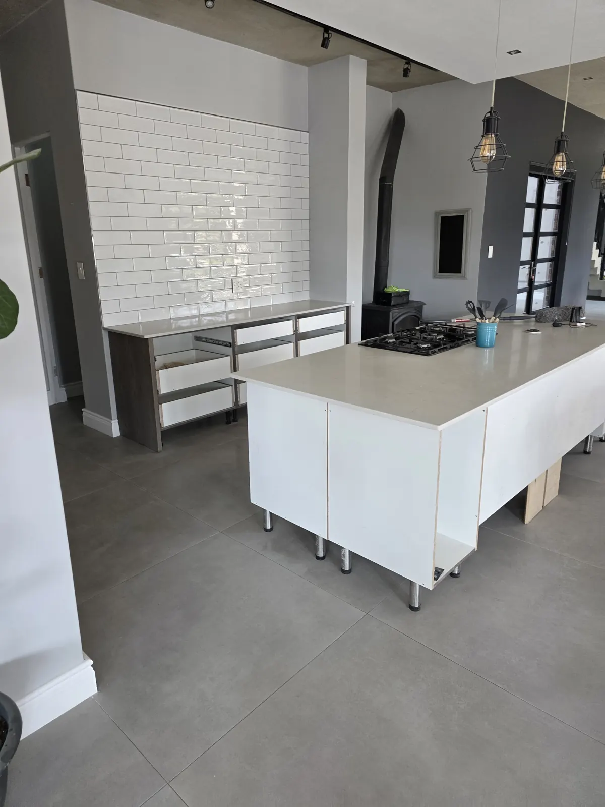 During: kitchen units and stone worktops being installed on new large-format floor tiles