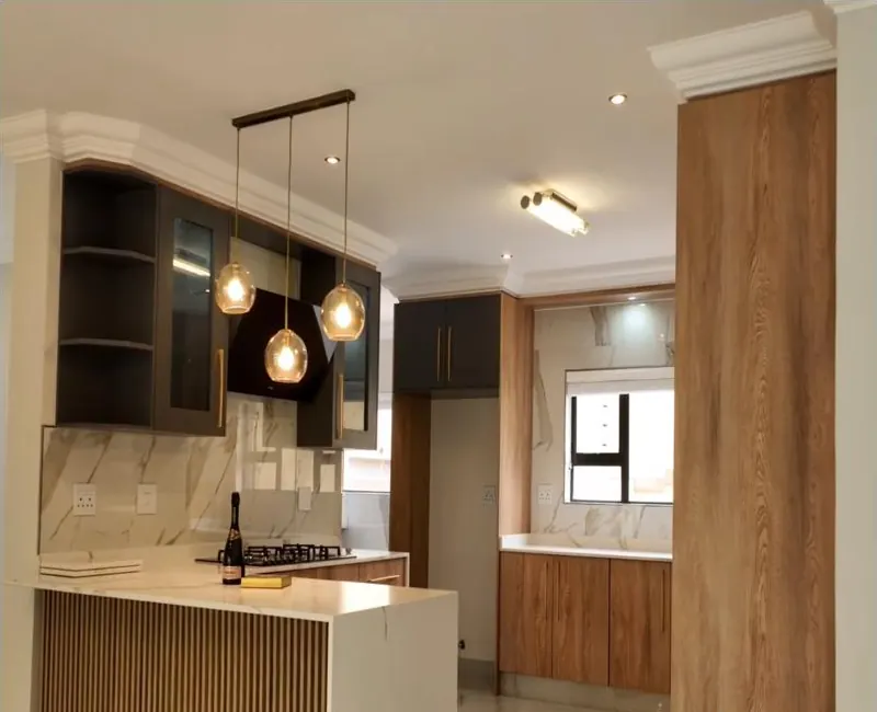 Kitchen with a timber-slatted peninsula, marble-look worktops and splashback, dark glass-fronted wall units and pendant lights