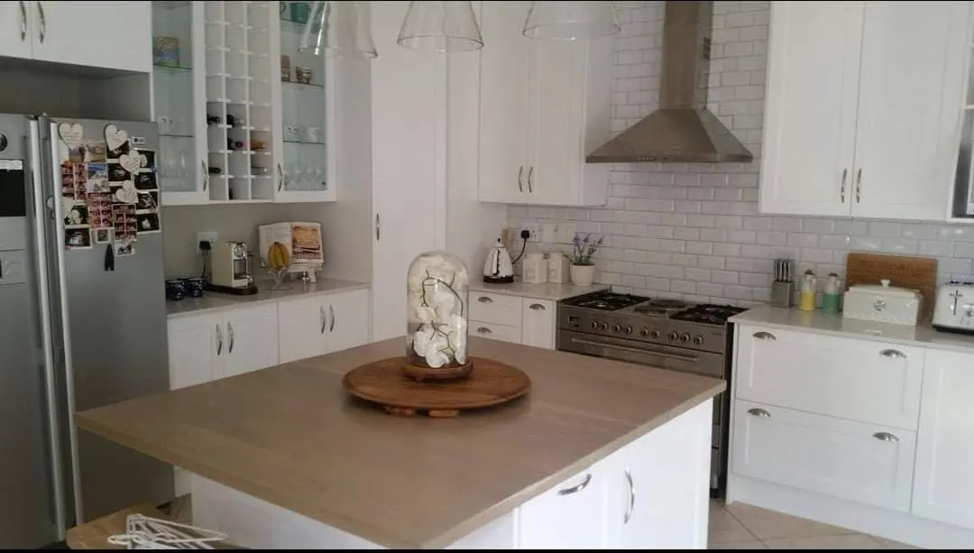 White shaker kitchen with subway tiles, range cooker and an oak-topped island