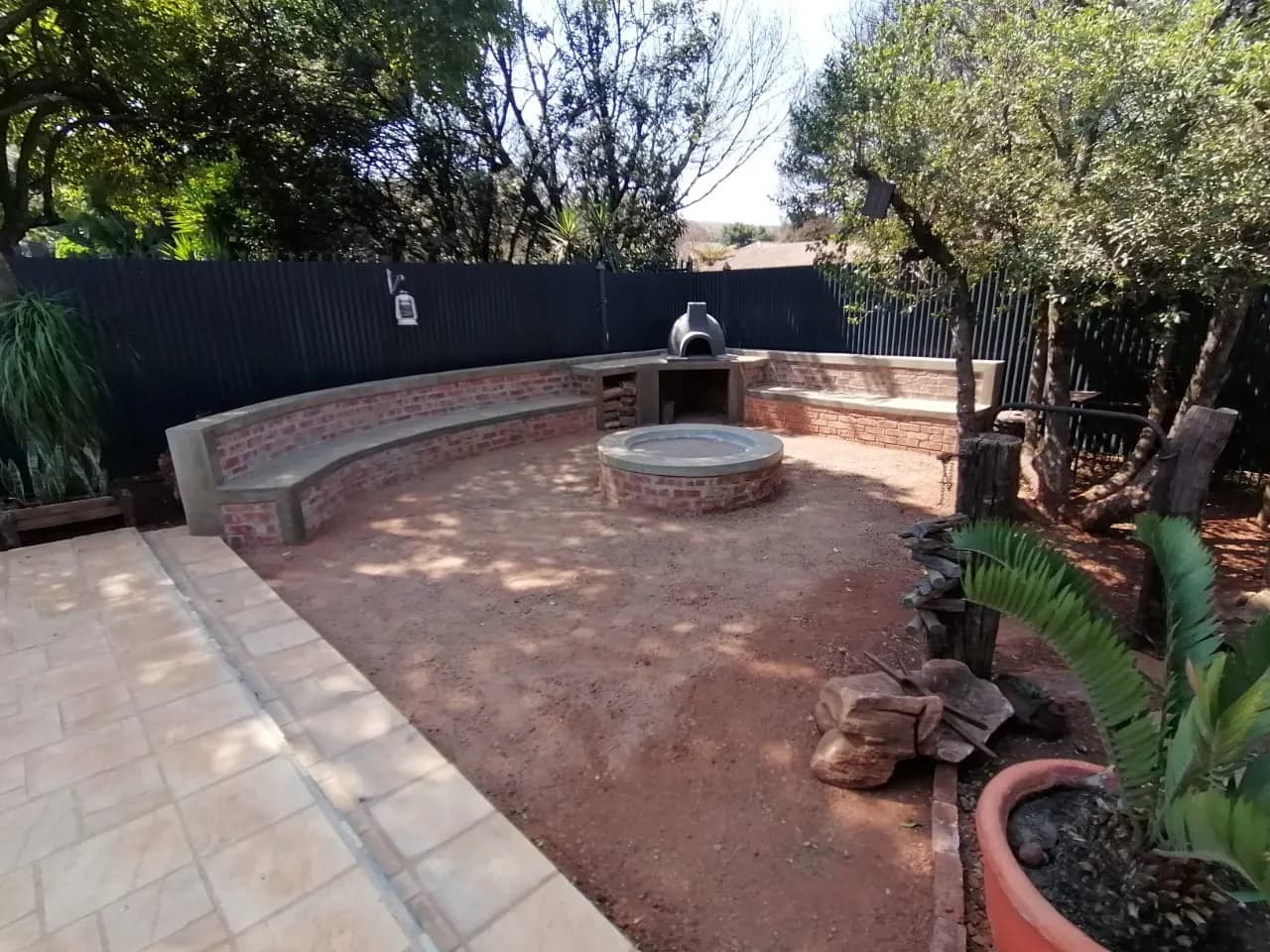 Curved brick garden seating around a fire pit with a pizza oven