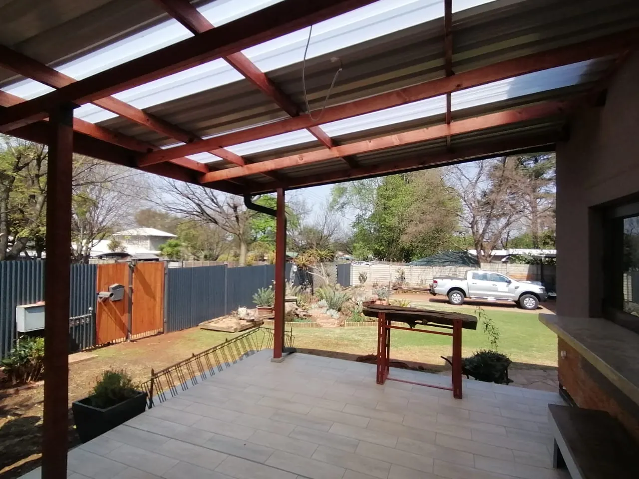 Timber-framed patio roof with clear sheeting over a tiled floor
