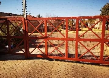 Before: red steel estate gates before maintenance and repainting