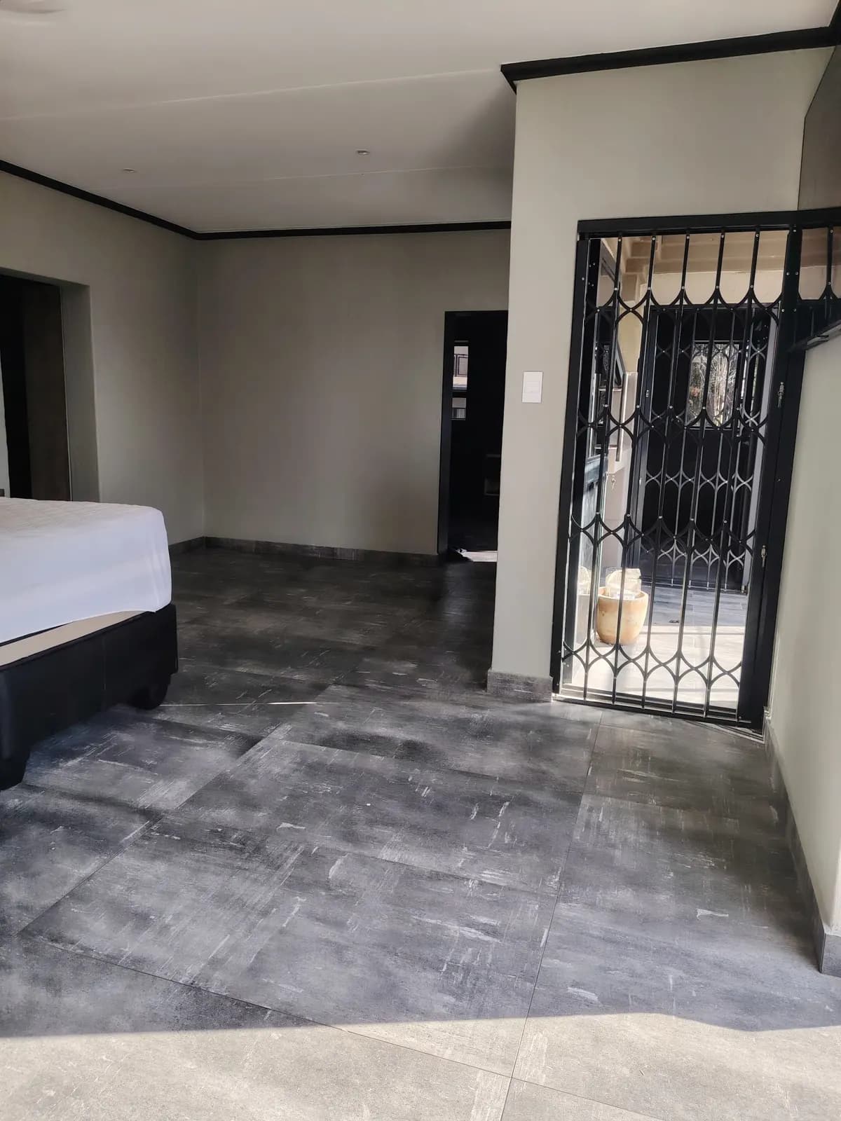 Bedroom with new large-format grey floor tiles, skirtings and black-painted cornices