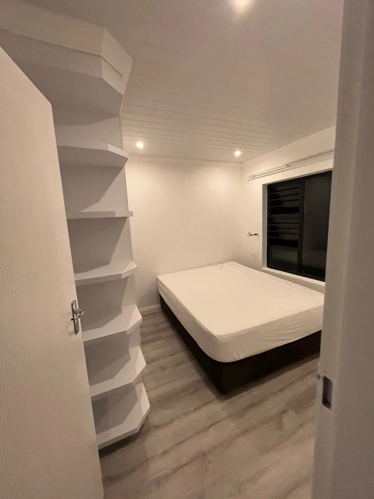 Renovated bedroom with built-in white shelving, downlights and laminate floor