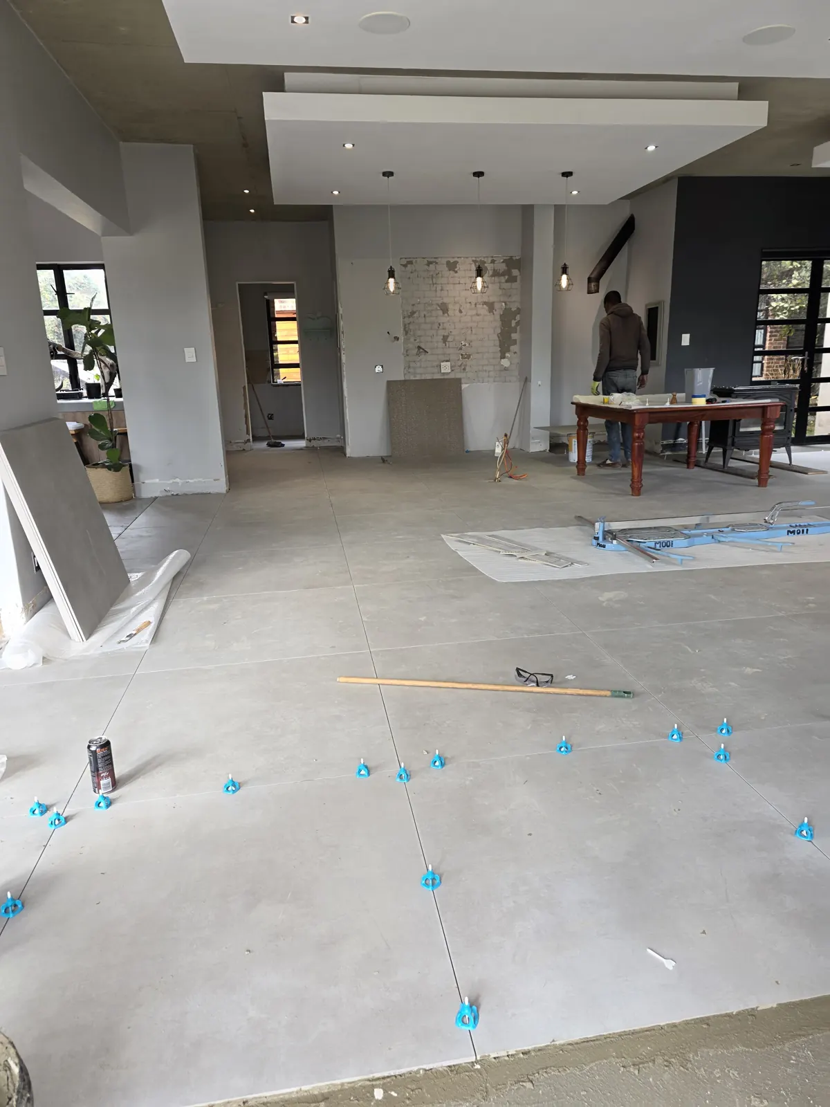 During: large-format floor tiles laid with levelling clips across an open-plan living area