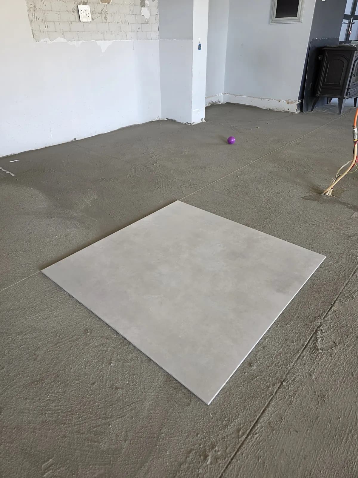During: new floor screed with the first large-format porcelain tile set out on a string line