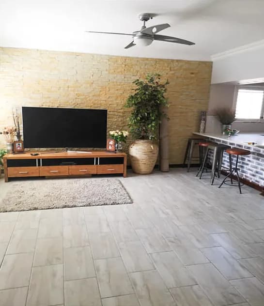 Lounge with a stacked-stone TV feature wall and wood-look floor tiles