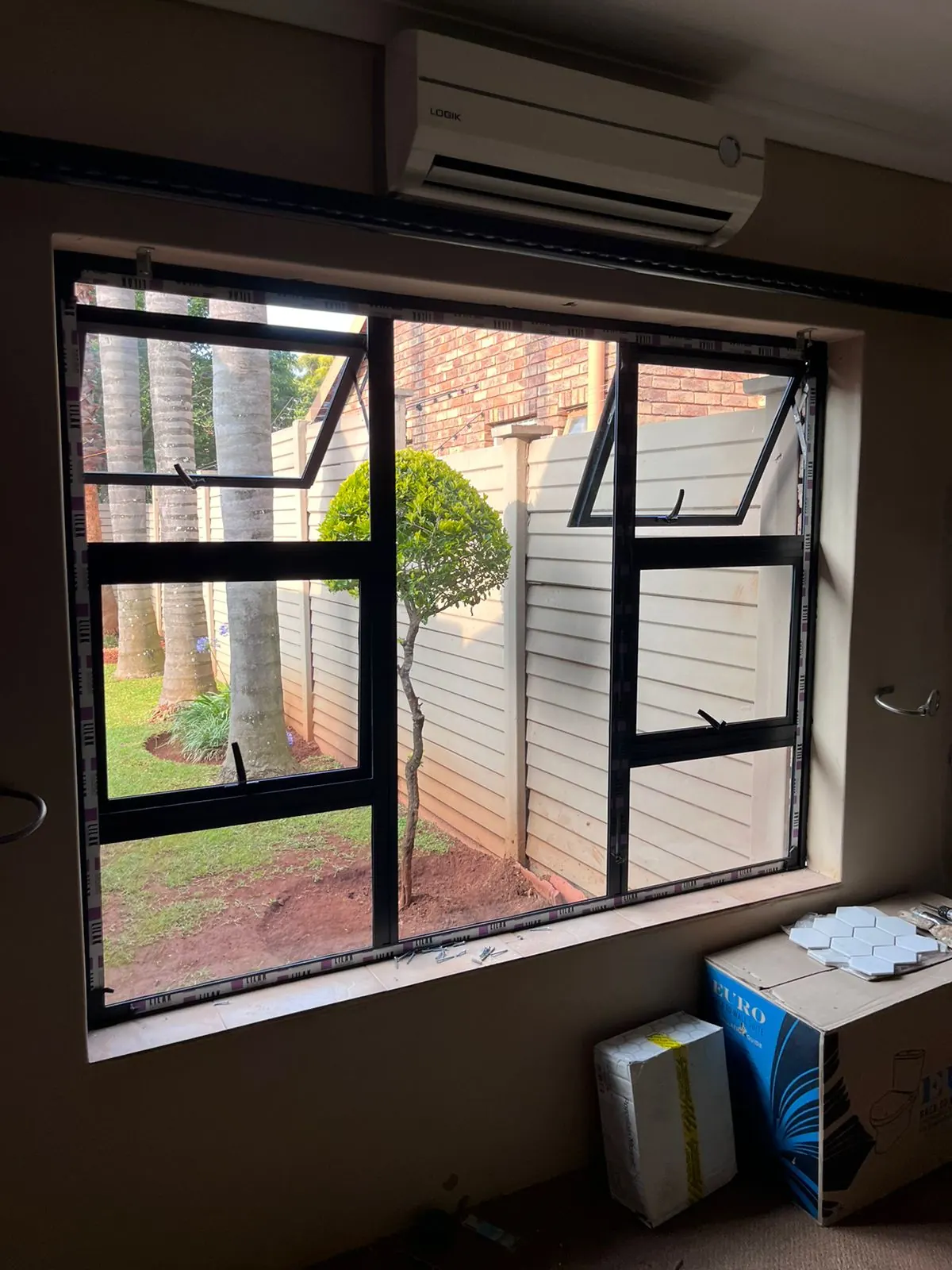 After: new black aluminium window with top-hung openers fitted in the same opening