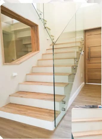 Staircase with solid timber treads, white risers and a frameless glass balustrade
