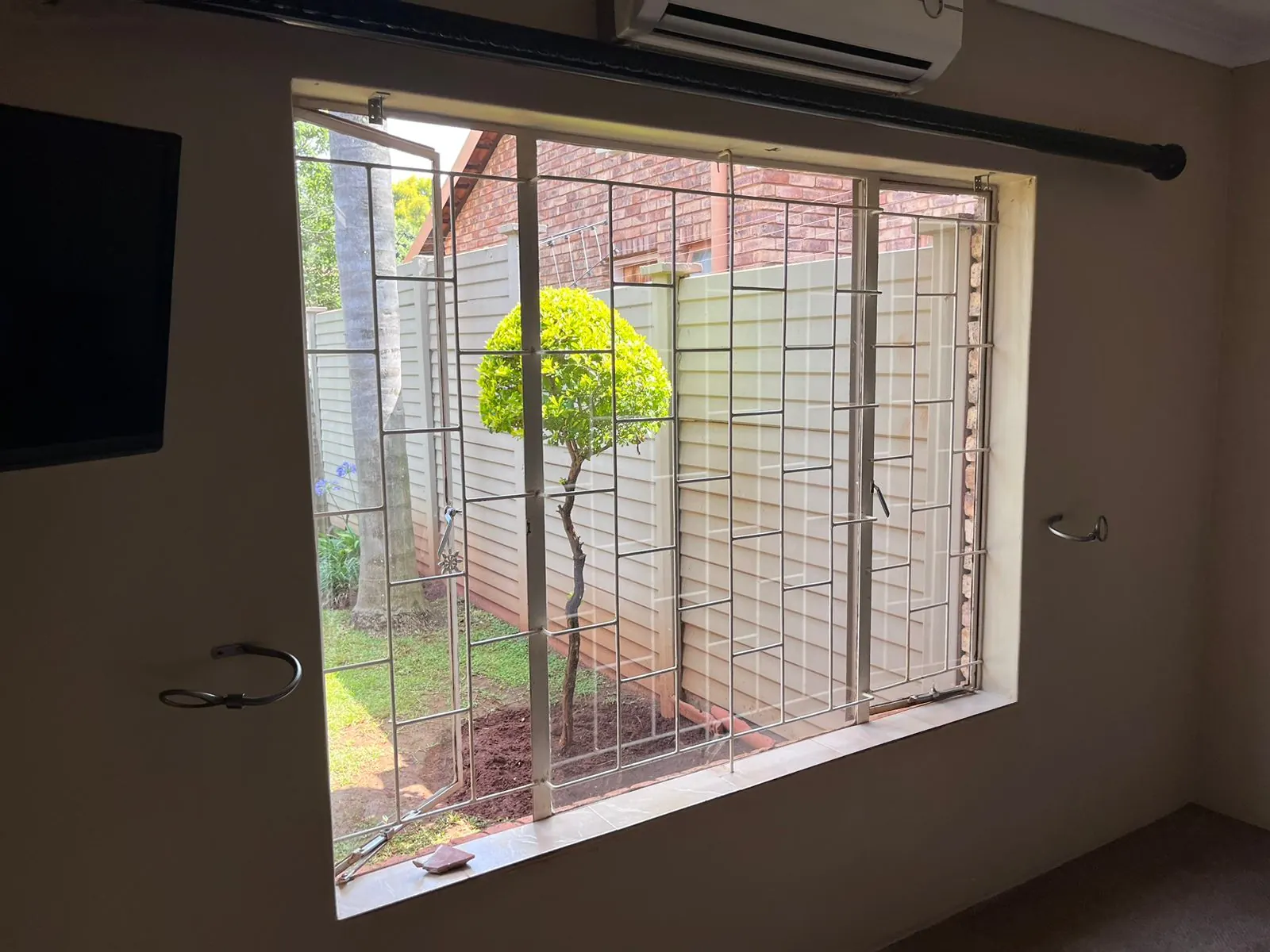 Before: old steel-framed bedroom window with burglar bars