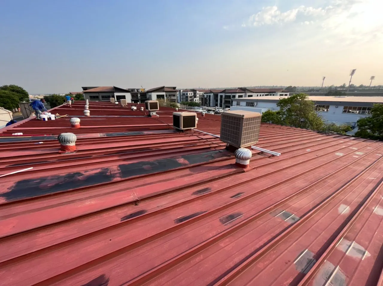Commercial IBR roof before coating, with patched joints and rooftop air coolers